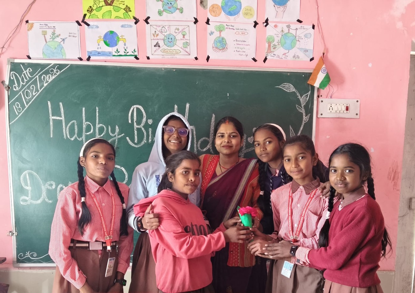 Students gathered with their teacher in front of a chalkboard decorated for a birthday celebration