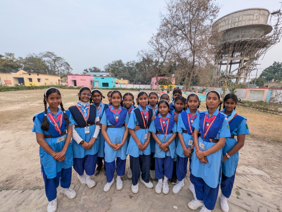 Girls in blue uniforms with ID badges standing together outdoors