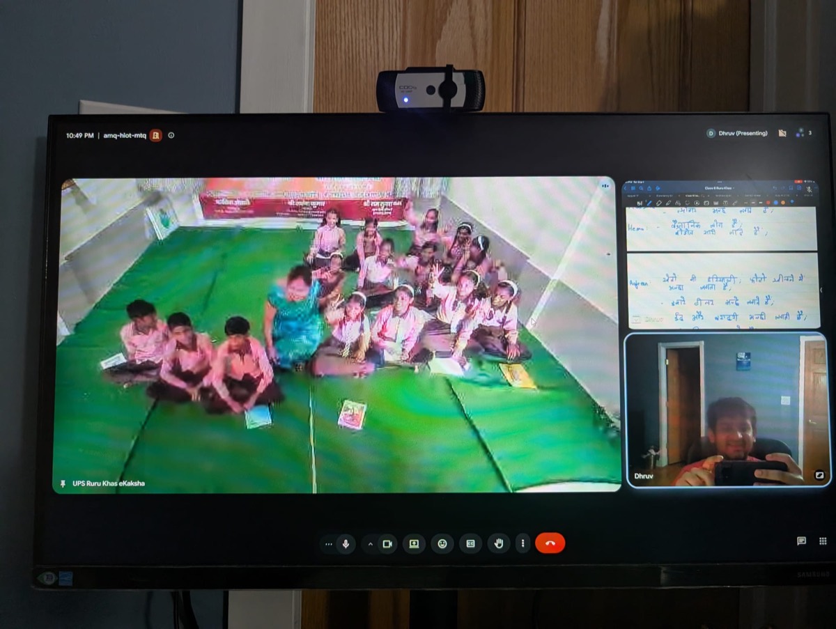 A classroom of students seated on the floor with their teacher during a virtual session