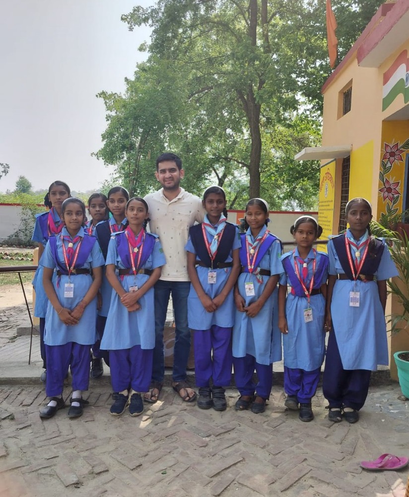 A volunteer educator standing with a group of girls in school uniforms