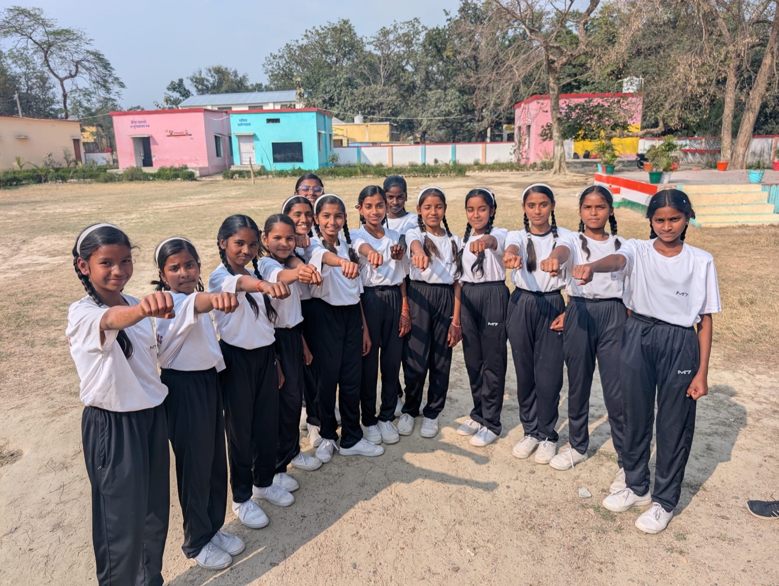 Smiling schoolgirls in white uniforms standing together outside their school